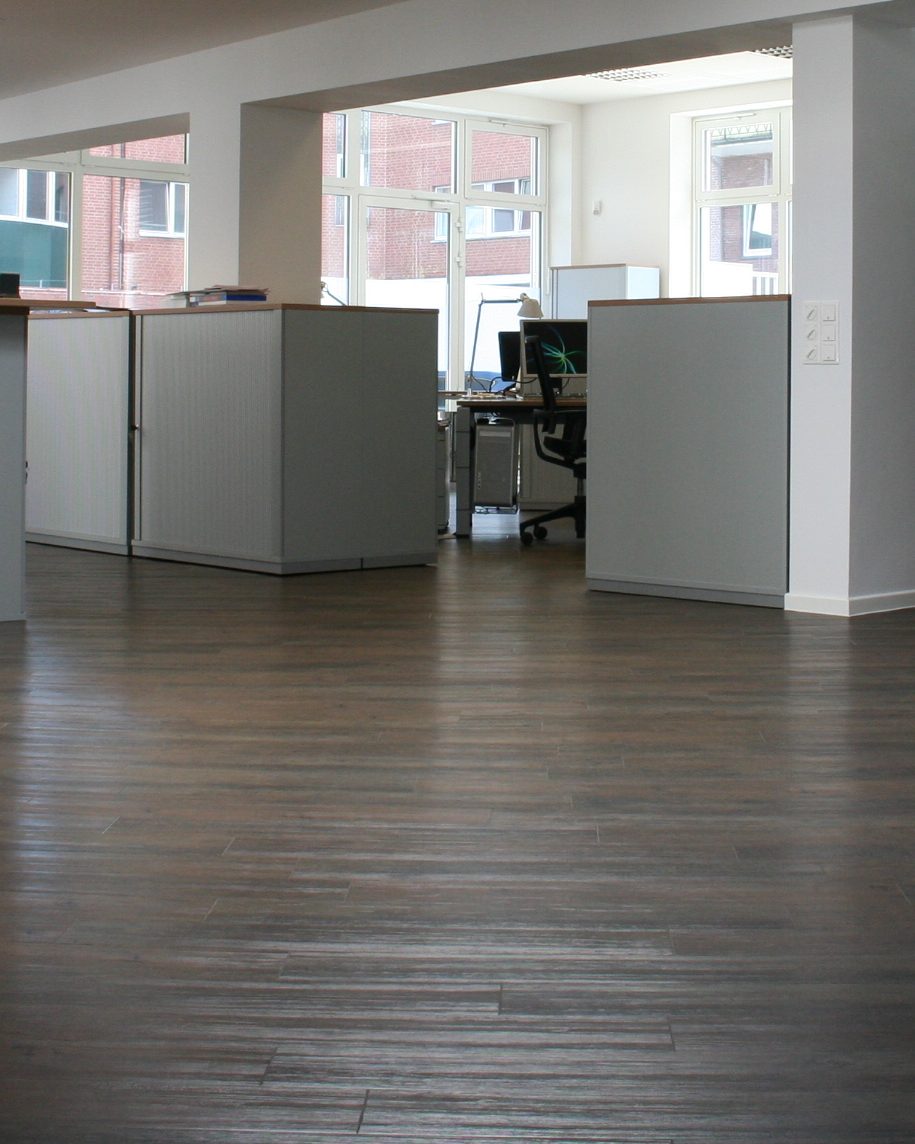 Helles Büro mit dunklem Holzboden, Arbeitsplätzen und großen Fenstern im Winterhuder Hof