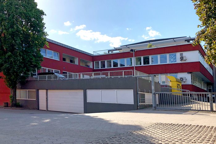 Haus Humboldtstraße 67a mit rot-weißer Fassade, Garagentoren und Hausnummernschild im Hof