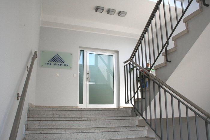 Helles Treppenhaus mit Glastür und Edelstahlgeländer