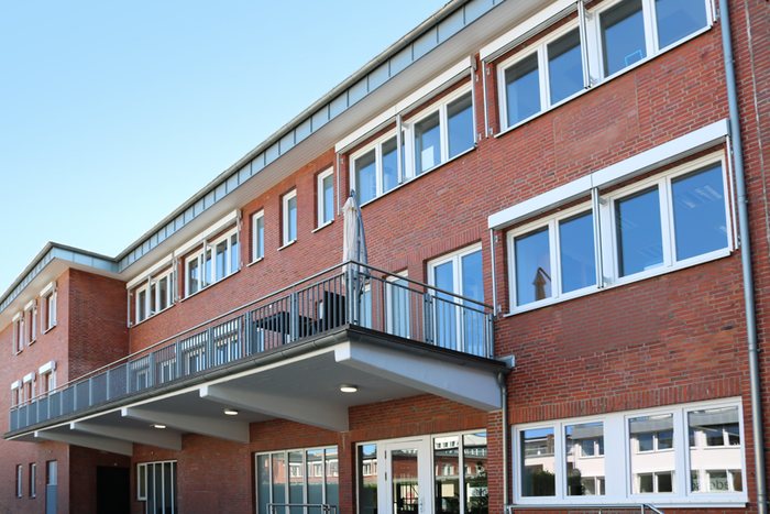 Klinkerhaus mit Balkon und großen Fenstern unter blauem Himmel